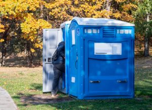 ada portable toilet in a park next to a walk way